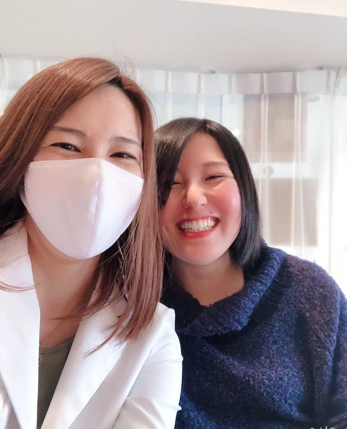 白衣姿の方と笑顔で並ぶ二人のサロンでの記念写真